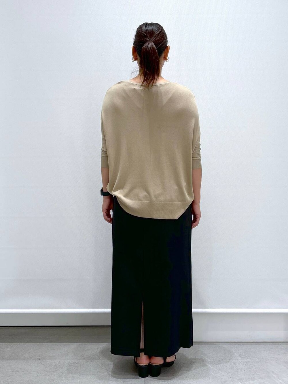 ブラック系のサンダル、ベージュ系のニット/セーター、ブラック系のスカートを着用したレディースの秋コーディネートの4枚目の写真