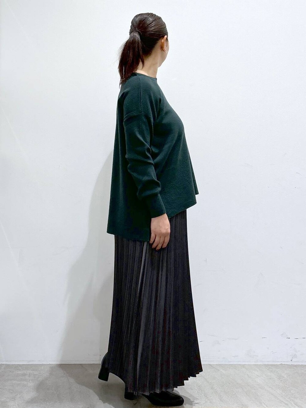 ブラック系のブーツ、グリーン系のニット/セーター、グレー系のスカートを着用したレディースの秋コーディネートの5枚目の写真