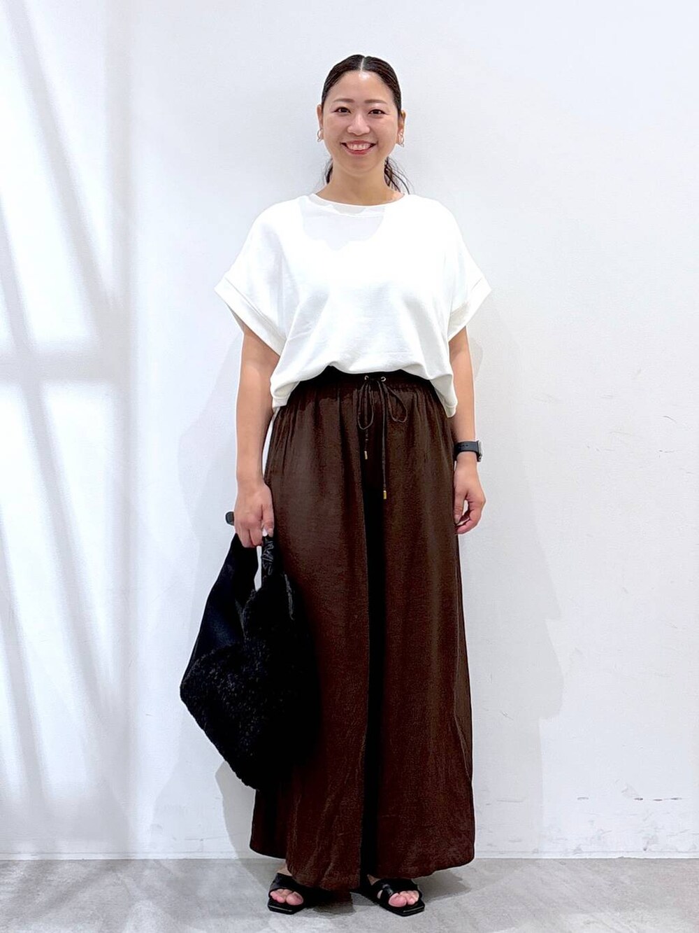 ブラウン系のその他パンツ、ブラック系のサンダル、ホワイト系のTシャツ/カットソーを着用したレディースの夏コーディネートの2枚目の写真