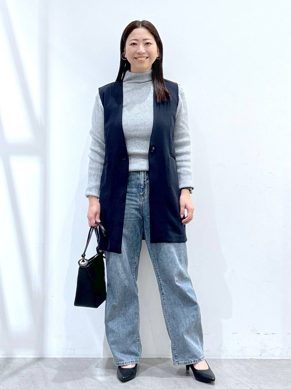 ブルー系のデニムパンツ、グレー系のニット/セーター、ブルー系のスーツベストを着用したレディースの冬コーディネートの2枚目の写真