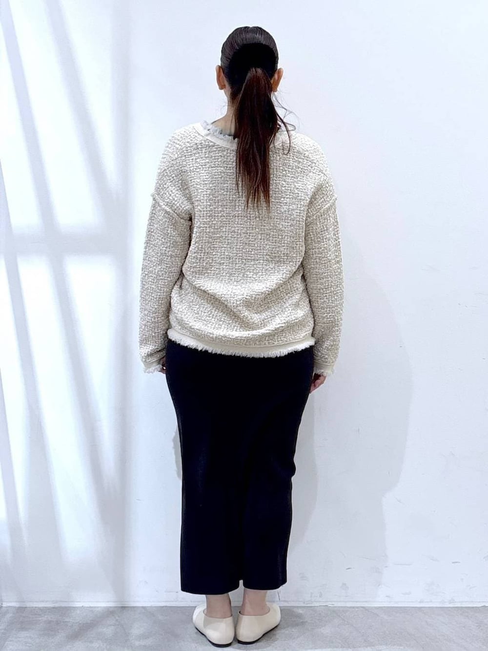 ベージュ系のスカート、ホワイト系のパンプス、ホワイト系のトートバッグを着用したレディースの冬コーディネートの4枚目の写真