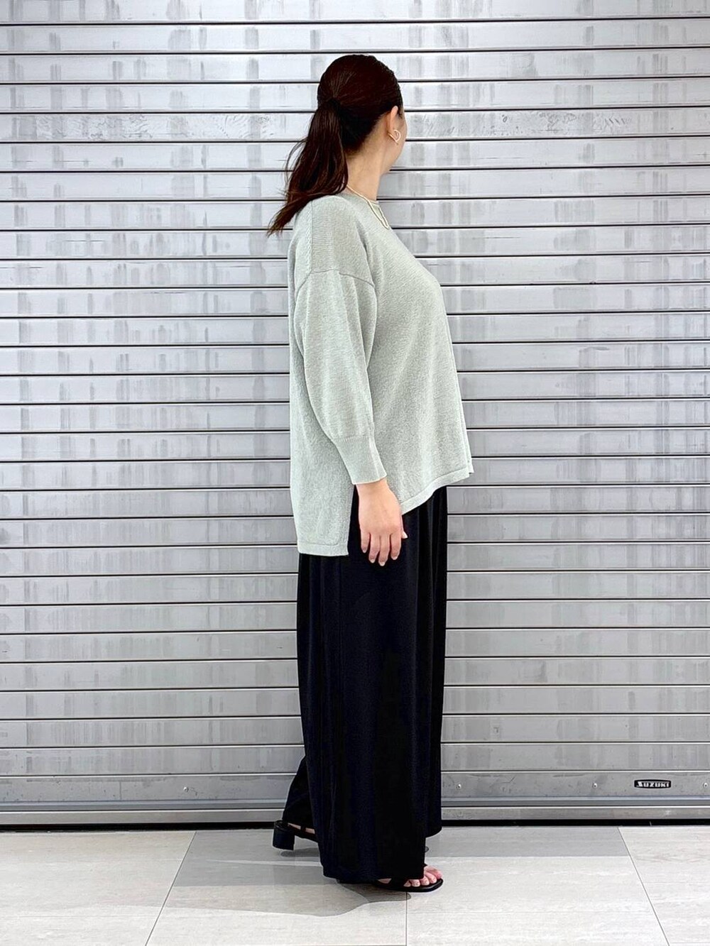ブラック系のハンドバッグ、ブラック系のその他パンツ、グリーン系のニット/セーターを着用したレディースの春コーディネートの5枚目の写真