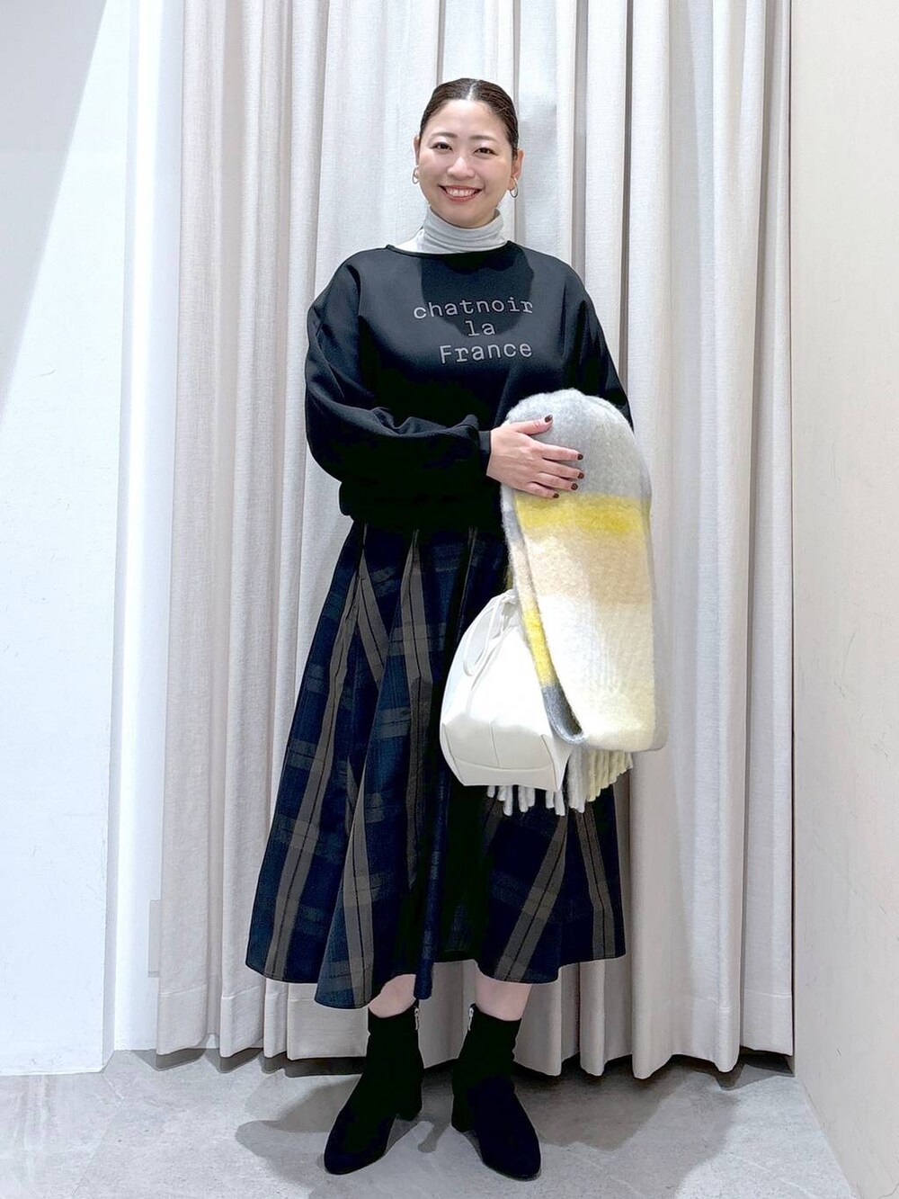 ブラック系のスウェット、ホワイト系のTシャツ/カットソー、グレー系のブーツを着用したレディースの秋コーディネートの2枚目の写真