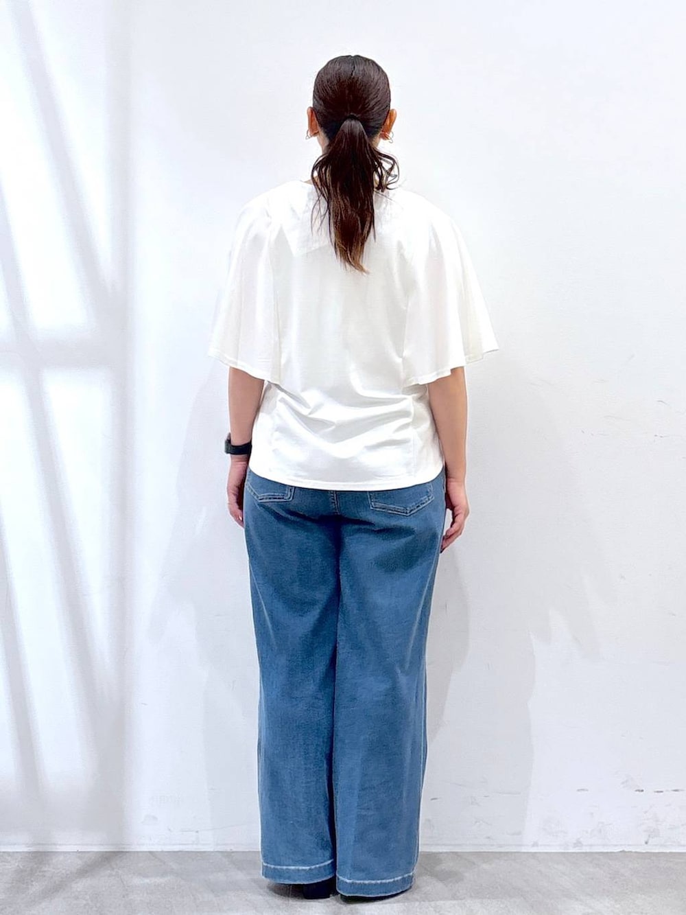 ブラック系のハンドバッグ、ブラック系のサンダル、ブルー系のデニムパンツを着用したレディースの夏コーディネートの4枚目の写真