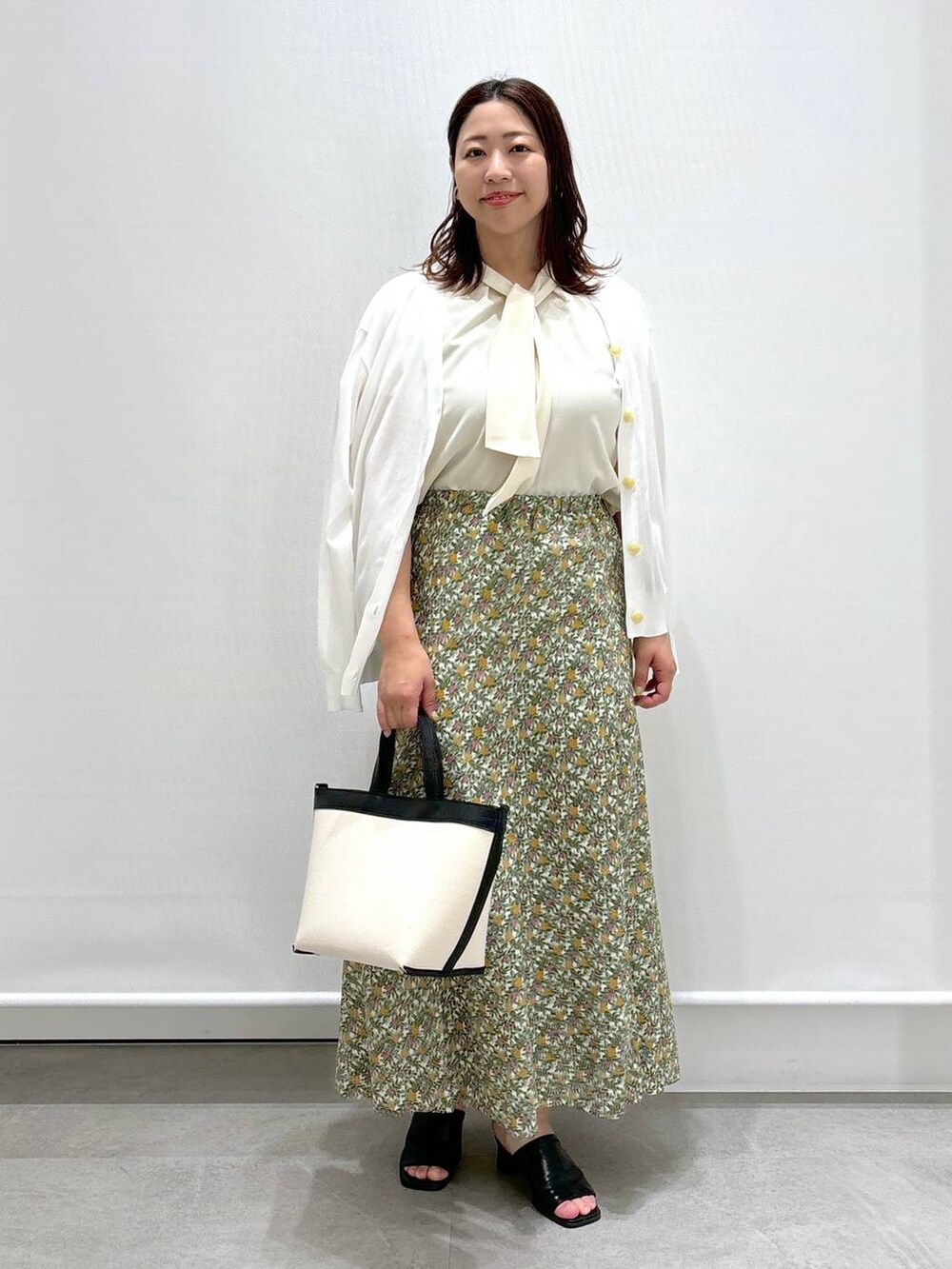 ホワイト系のシャツ/ブラウス、ホワイト系のスカート、ブラック系のサンダルを着用したレディースの春コーディネートの2枚目の写真