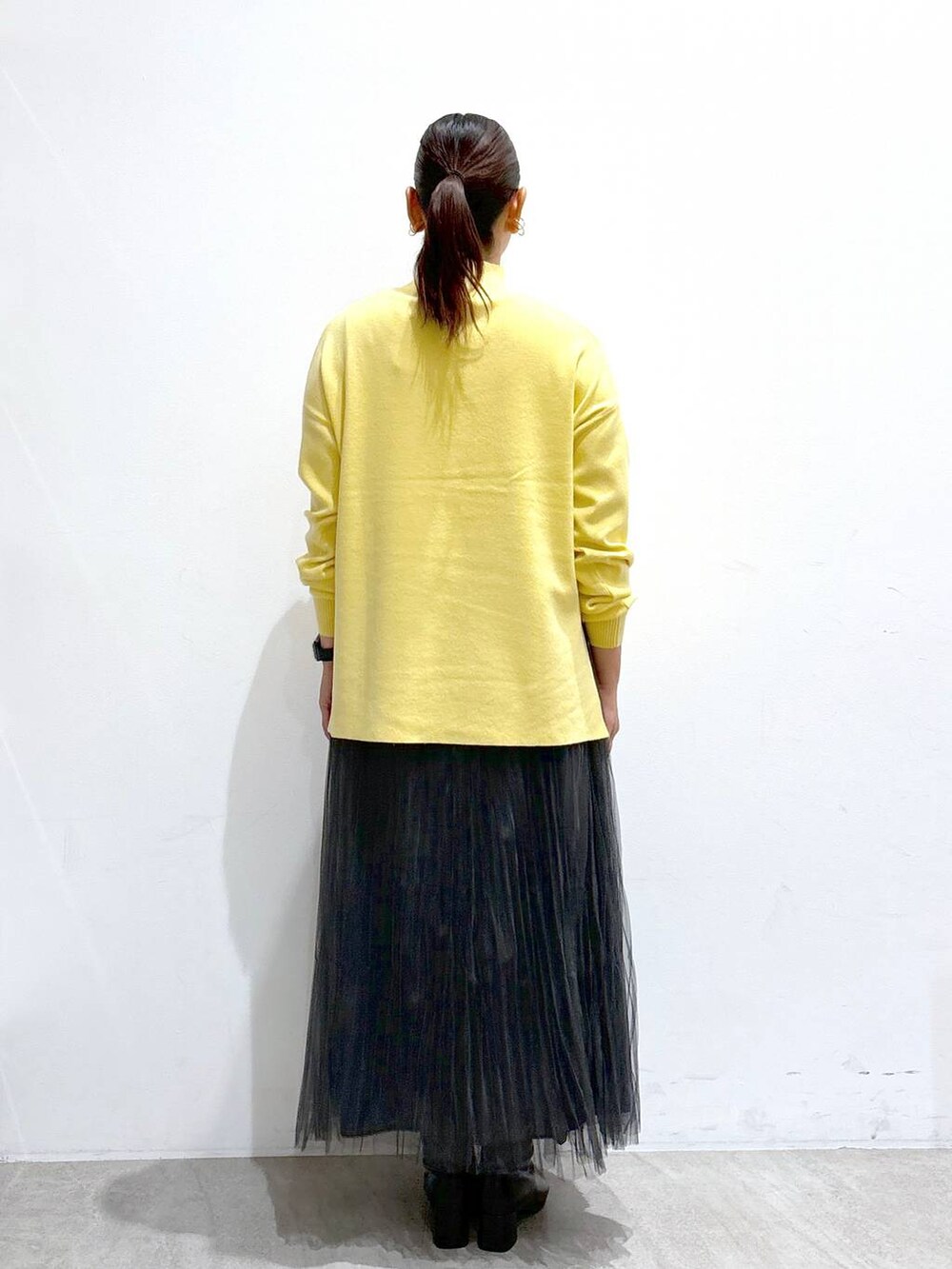 ブラック系のハンドバッグ、グレー系のスカート、ブラック系のブーツを着用したレディースの秋コーディネートの4枚目の写真