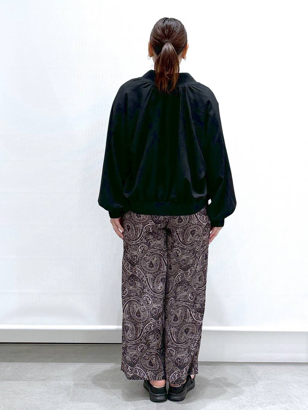 ホワイト系のTシャツ/カットソー、ブラック系のサンダル、ブラック系のブルゾンを着用したレディースの春コーディネートの4枚目の写真