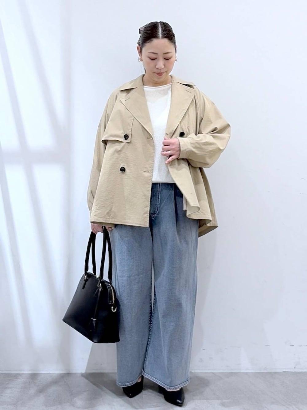 ホワイト系のニット/セーター、ブルー系のデニムパンツ、ブラック系のハンドバッグを着用したレディースの春コーディネートの2枚目の写真