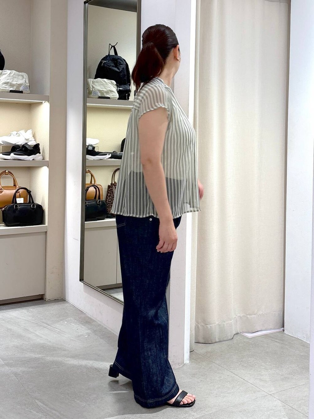 グレー系のシャツ/ブラウス、ブルー系のデニムパンツ、ブラック系のハンドバッグを着用したレディースの夏コーディネートの4枚目の写真