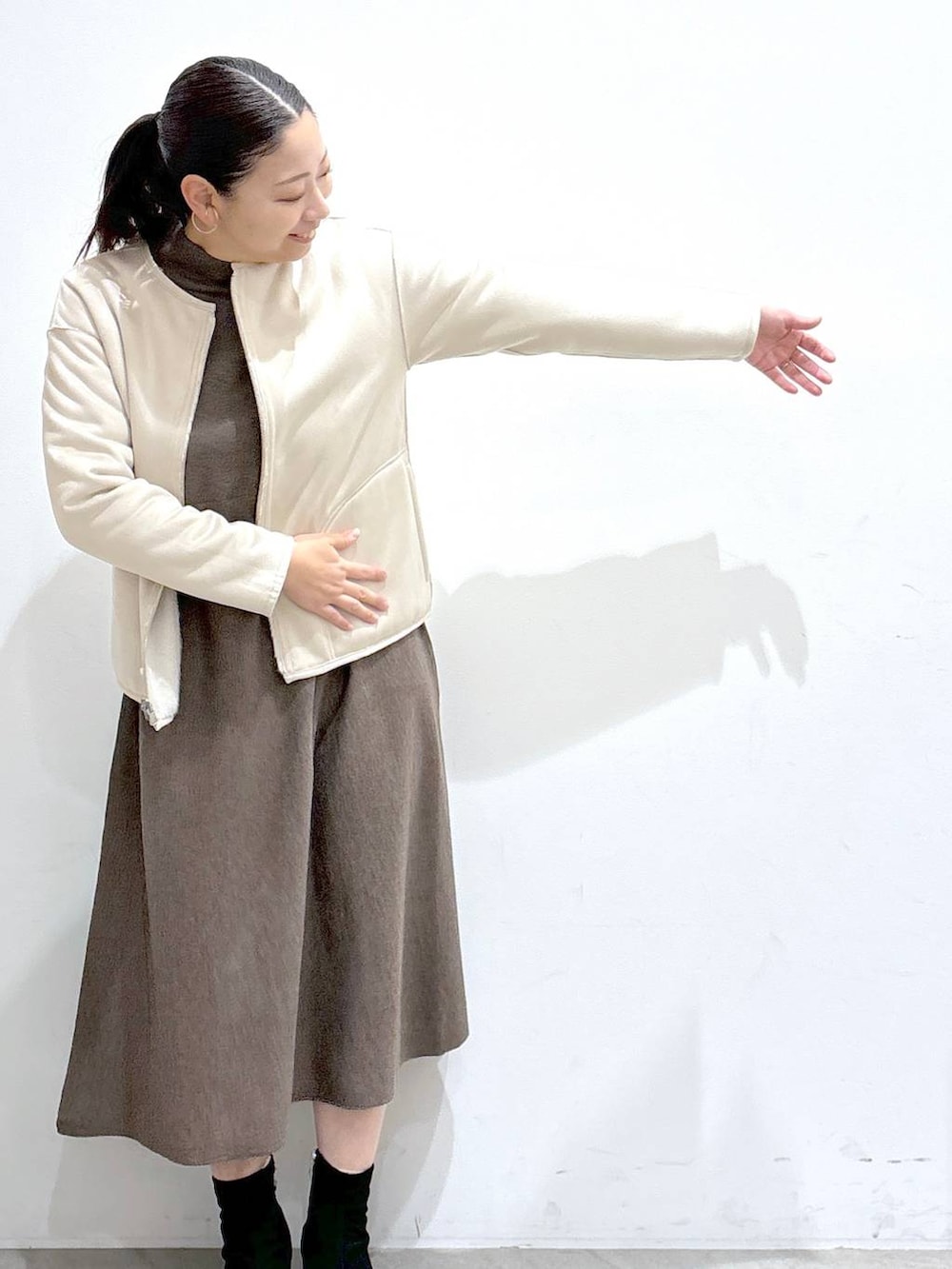 グレー系のブーツ、ベージュ系のムートンコート、ブラック系のハンドバッグを着用したレディースの冬コーディネートの6枚目の写真