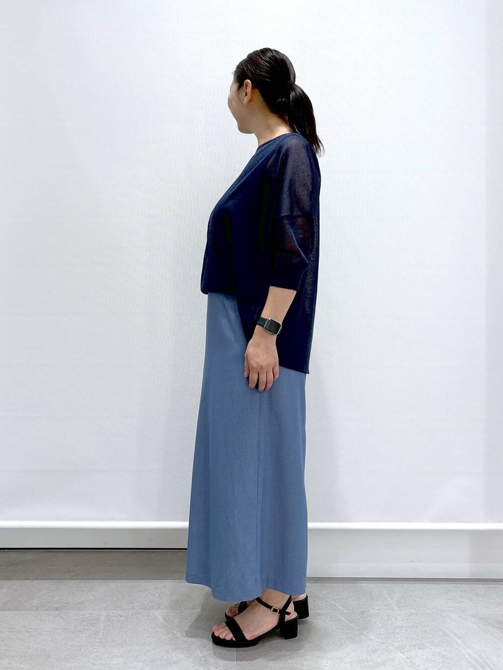 ブラック系のショルダーバッグ、ブラック系のサンダル、ブルー系のニット/セーターを着用したレディースの夏コーディネートの3枚目の写真