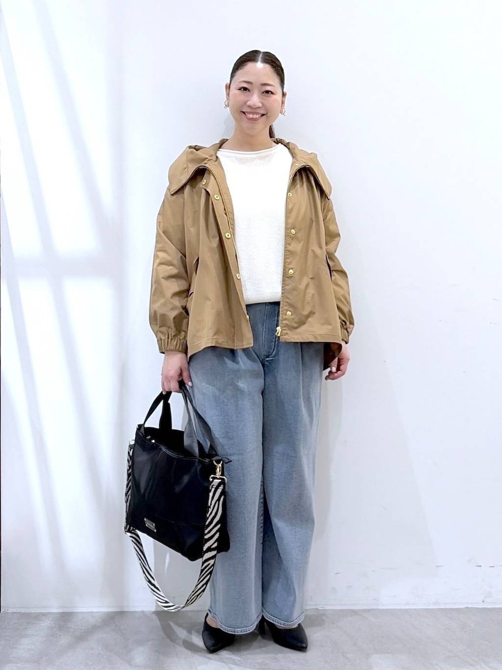 ブラック系のトートバッグ、ホワイト系のニット/セーター、ブルー系のデニムパンツを着用したレディースの春コーディネートの2枚目の写真