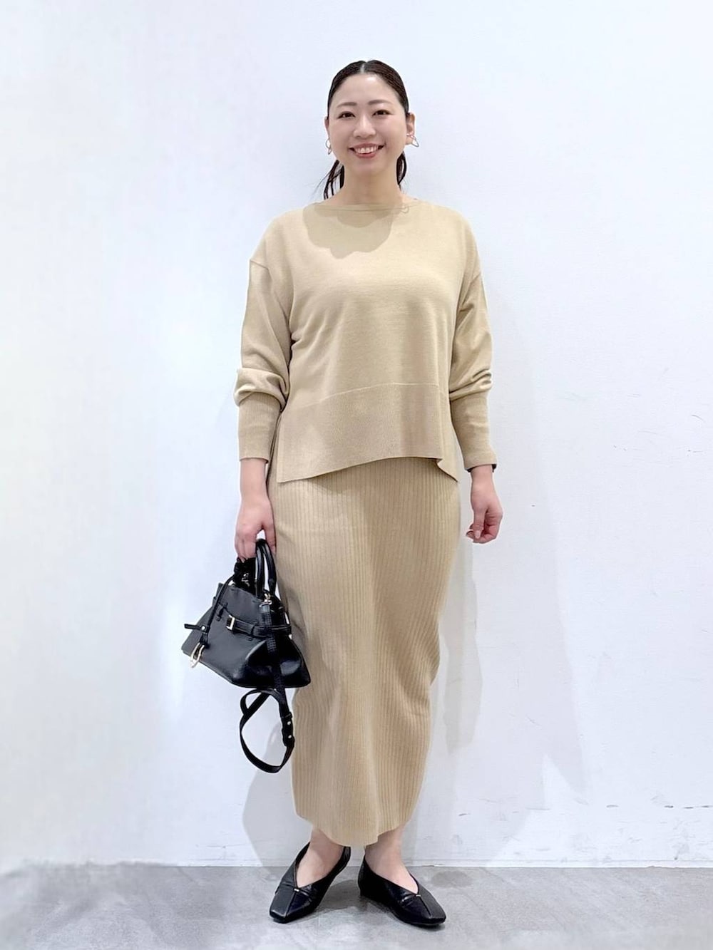 ベージュ系のニット/セーター、ベージュ系のスカート、ブラック系のパンプスを着用したレディースの冬コーディネートの2枚目の写真