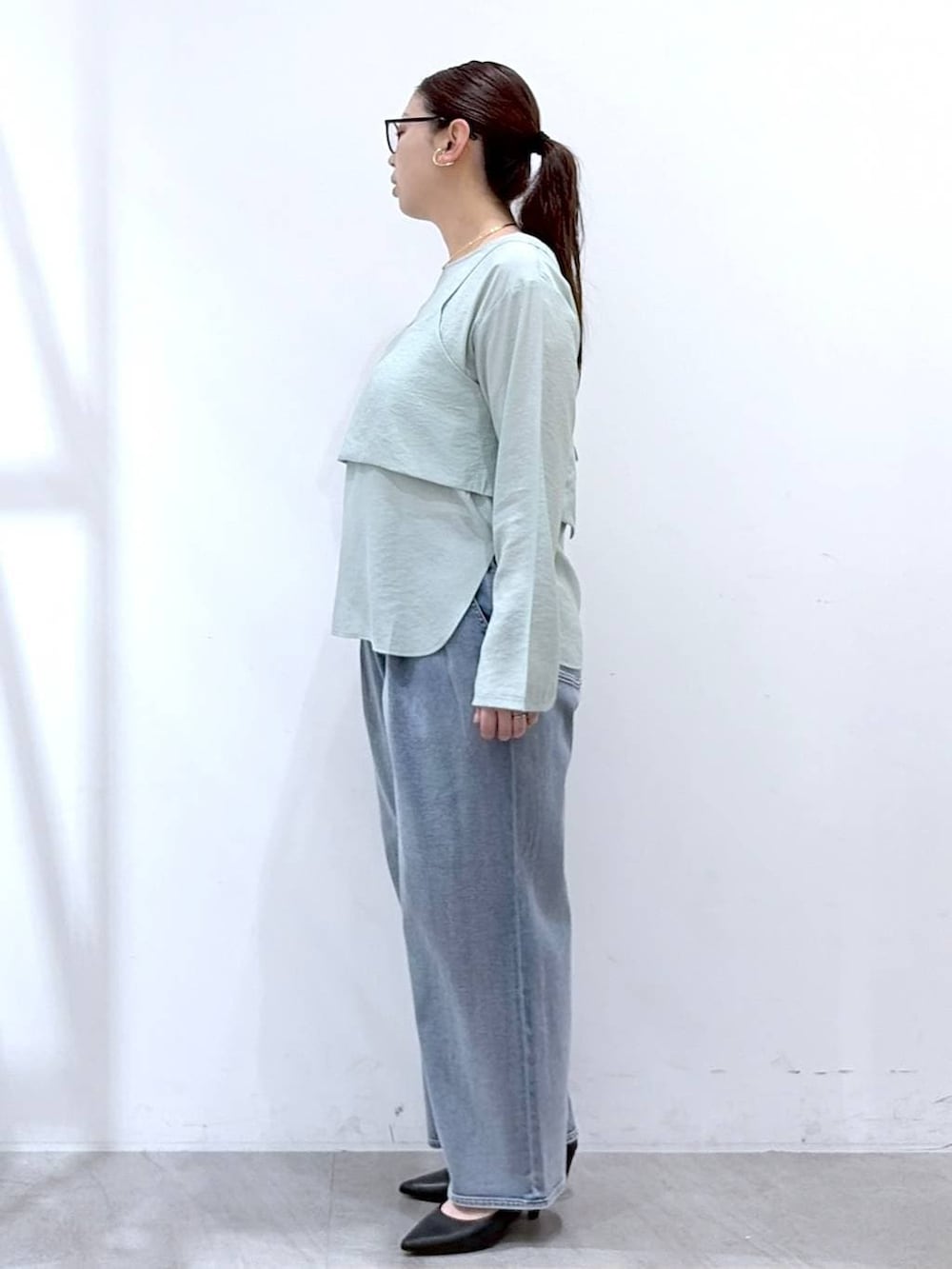 ブルー系のデニムパンツ、ブラック系のハンドバッグ、グリーン系のシャツ/ブラウスを着用したレディースの春コーディネートの3枚目の写真