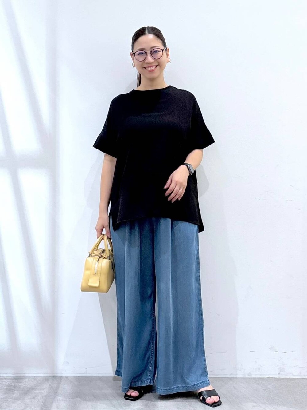 ブラック系のシャツ/ブラウス、ブラック系のサンダル、ブルー系のデニムパンツを着用したレディースの夏コーディネートの2枚目の写真