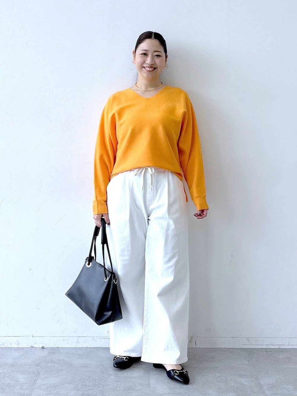 ホワイト系のデニムパンツ、ブラック系のパンプス、ブラック系のトートバッグを着用したレディースの春コーディネートの2枚目の写真