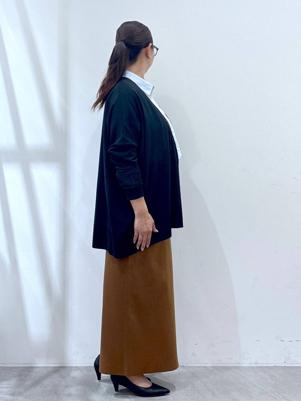 ブラック系のパンプス、ブラック系のカーディガン/ボレロ、イエロー系のスカートを着用したレディースの秋コーディネートの5枚目の写真