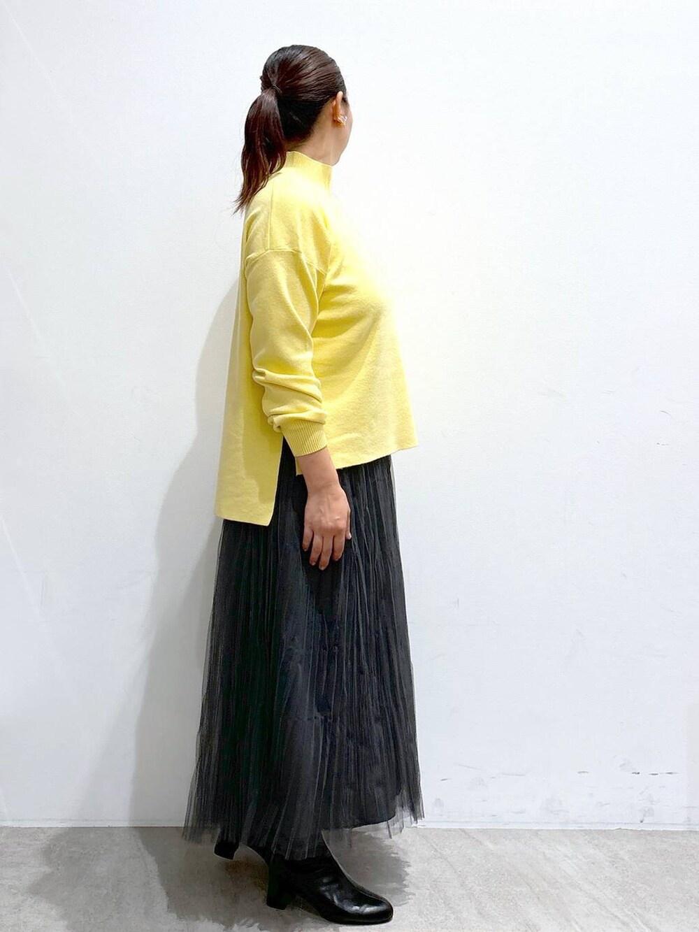 ブラック系のハンドバッグ、グレー系のスカート、ブラック系のブーツを着用したレディースの秋コーディネートの5枚目の写真