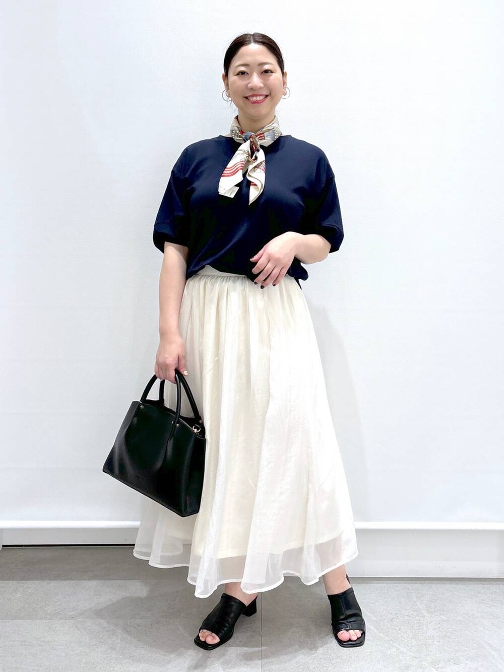 ホワイト系のスカート、ブラック系のショルダーバッグ、ブラック系のサンダルを着用したレディースの春コーディネートの2枚目の写真