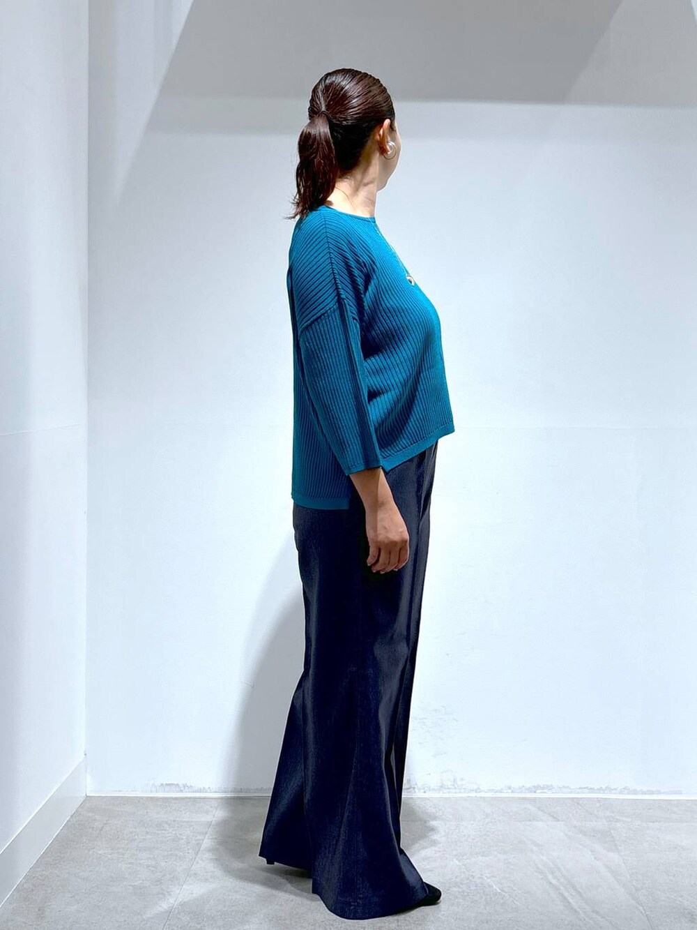 ブルー系のニット/セーター、ブラック系のパンプス、ブルー系のデニムパンツを着用したレディースの秋コーディネートの5枚目の写真