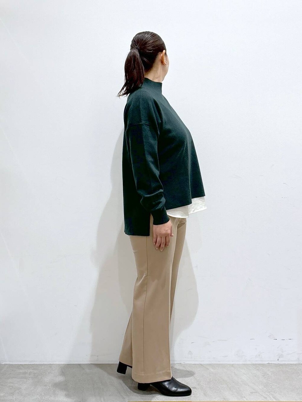 ホワイト系のシャツ/ブラウス、ブラック系のブーツ、グリーン系のニット/セーターを着用したレディースの秋コーディネートの5枚目の写真