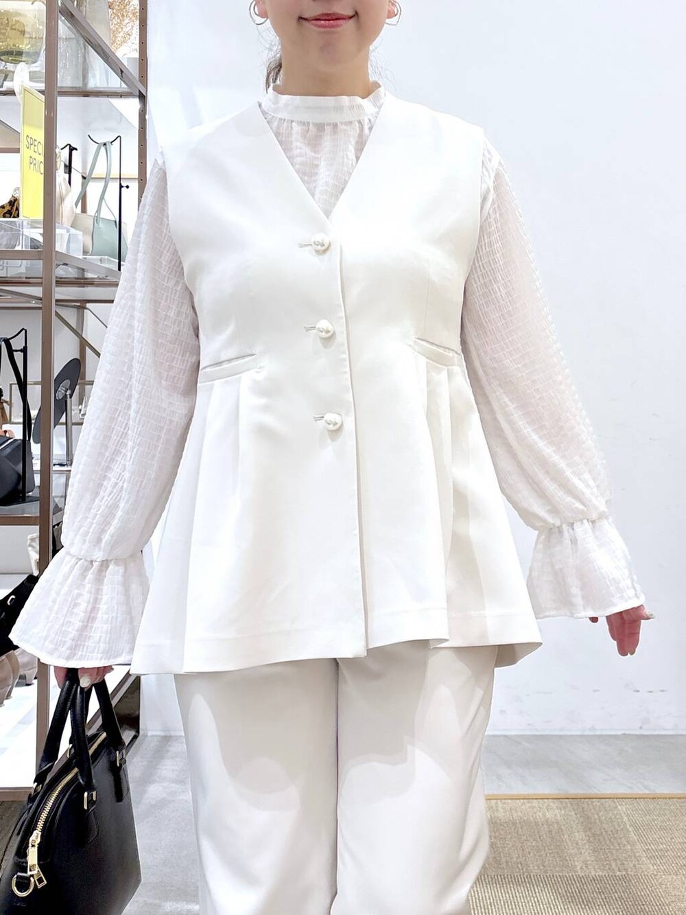 ブラック系のハンドバッグ、ホワイト系のシャツ/ブラウス、ホワイト系のベストを着用したレディースの冬コーディネートの6枚目の写真