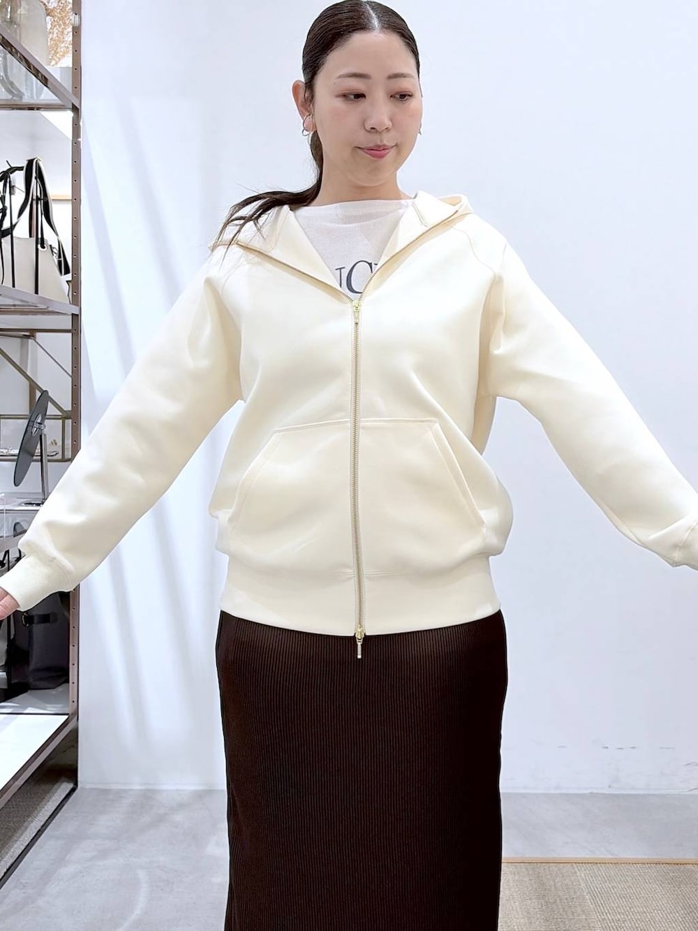 ホワイト系のパーカー、ブラウン系のスカート、ブラック系のショルダーバッグを着用したレディースの春コーディネートの7枚目の写真