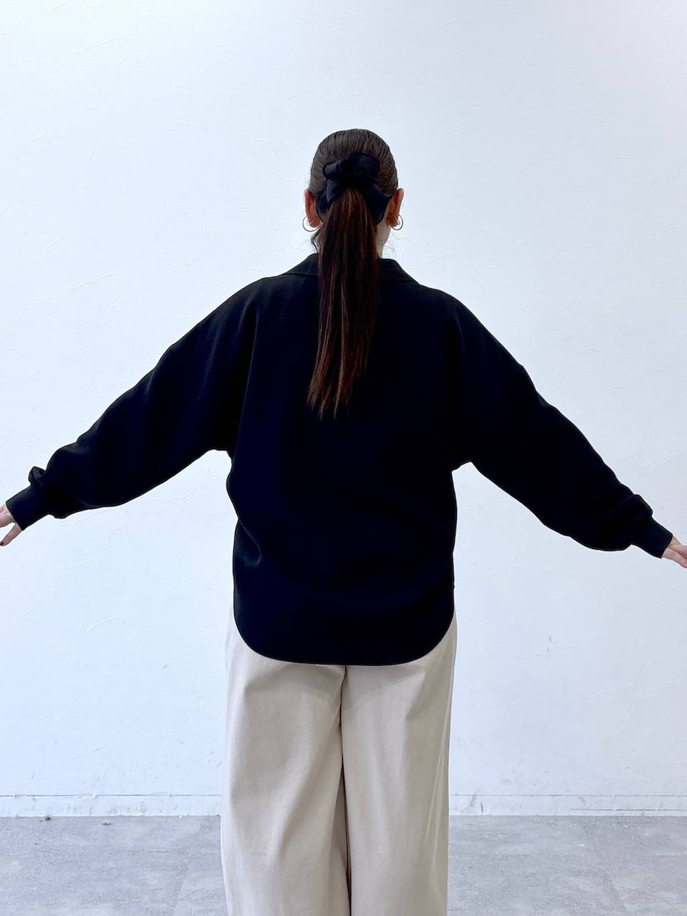 ブラック系のハンドバッグ、ベージュ系のデニムパンツ、ブラック系のパンプスを着用したレディースの冬コーディネートの6枚目の写真