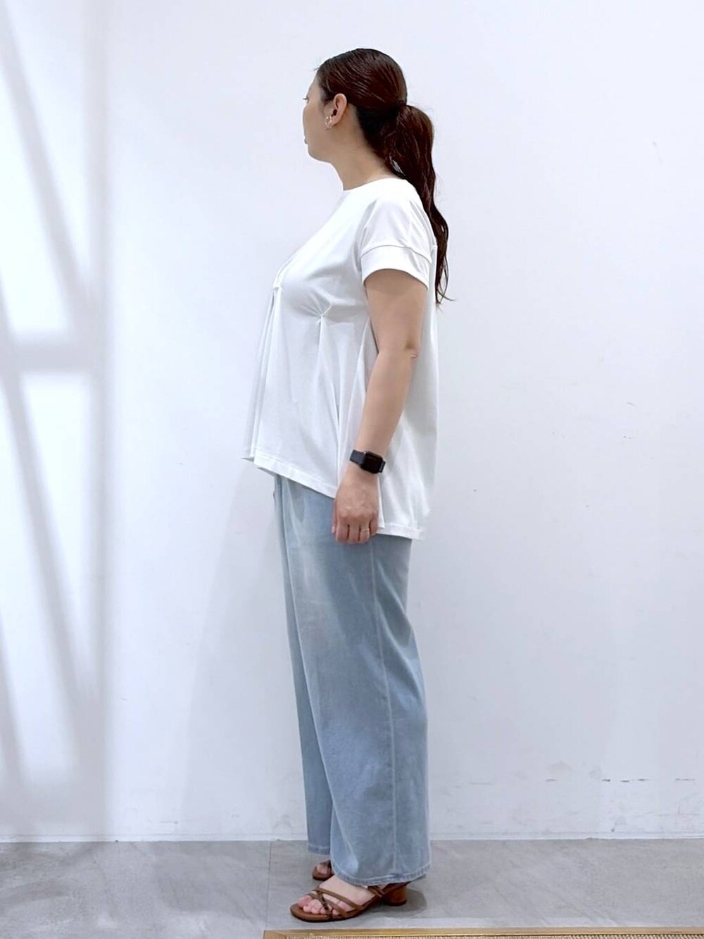 ブラウン系のサンダル、ブラウン系のハンドバッグ、ホワイト系のTシャツ/カットソーを着用したレディースの夏コーディネートの3枚目の写真