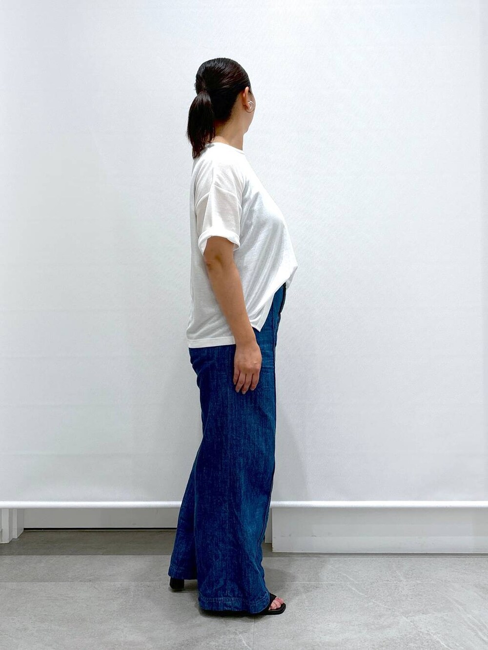 ブルー系のデニムパンツ、ブラック系のサンダル、ホワイト系のTシャツ/カットソーを着用したレディースの夏コーディネートの4枚目の写真