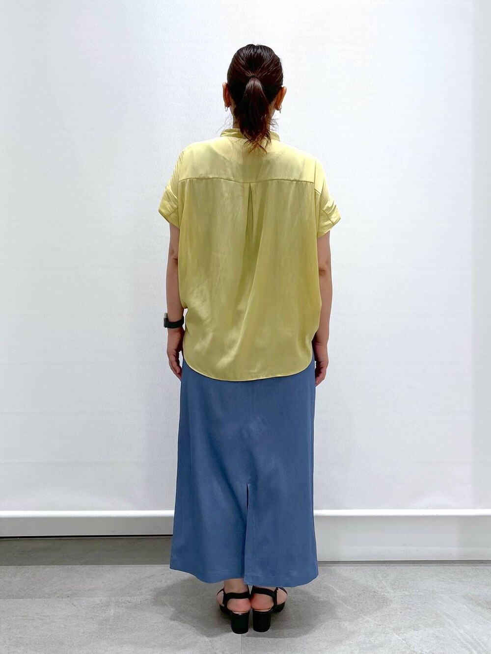 イエロー系のシャツ/ブラウス、ブラック系のサンダル、ブラック系のハンドバッグを着用したレディースの夏コーディネートの3枚目の写真