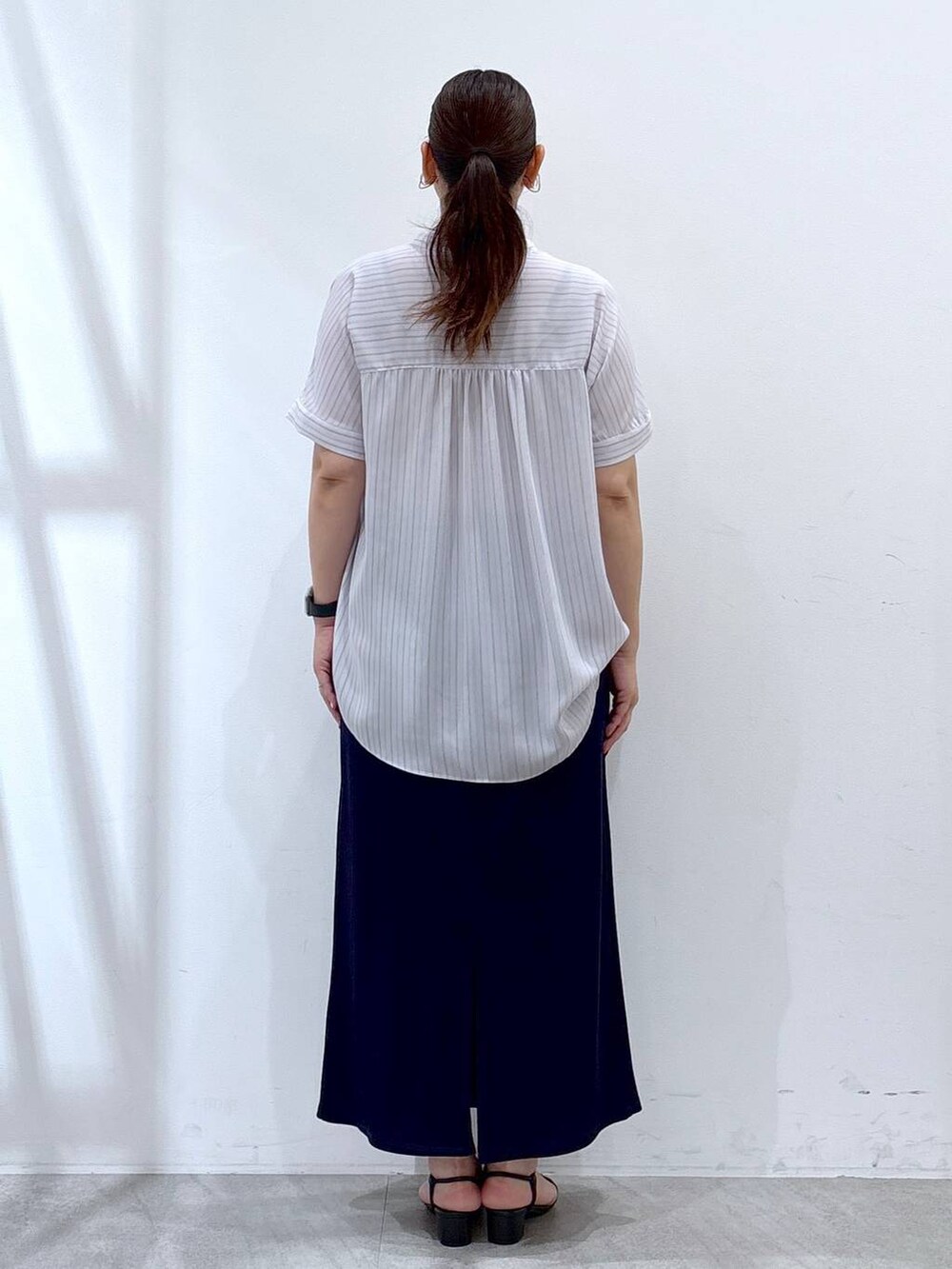 ブルー系のスカート、ブラック系のハンドバッグ、ブルー系のシャツ/ブラウスを着用したレディースの夏コーディネートの4枚目の写真