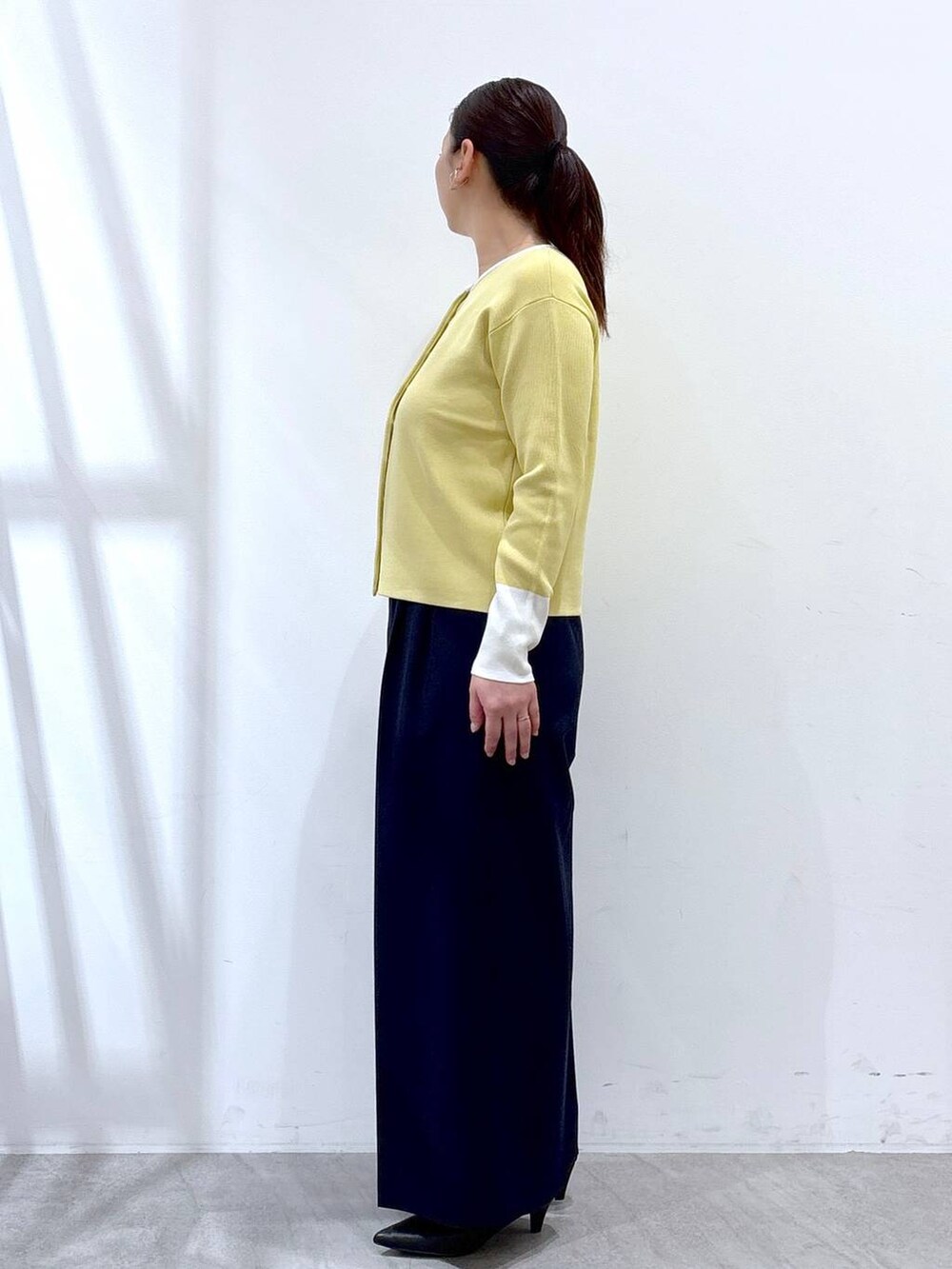 ブラック系のハンドバッグ、ブルー系のその他パンツ、イエロー系のカーディガン/ボレロを着用したレディースの春コーディネートの3枚目の写真