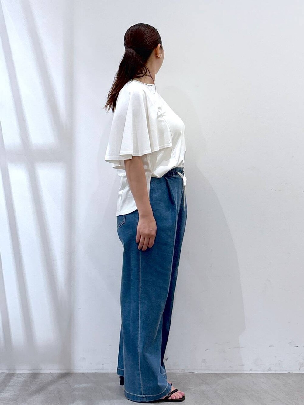 ブラック系のハンドバッグ、ブラック系のサンダル、ブルー系のデニムパンツを着用したレディースの夏コーディネートの5枚目の写真