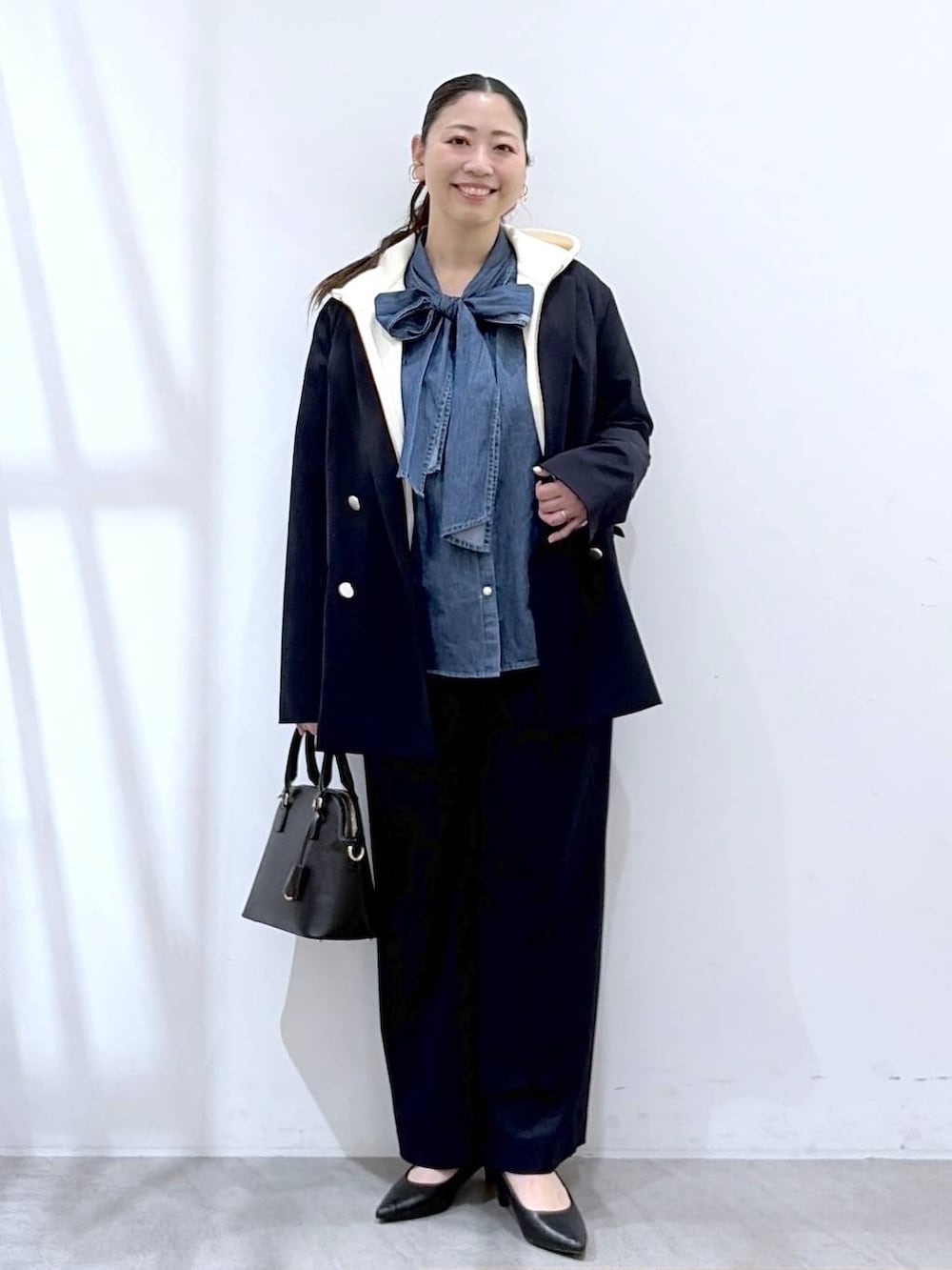 ブラック系のハンドバッグ、ホワイト系のパーカー、ブルー系のその他パンツを着用したレディースの春コーディネートの2枚目の写真