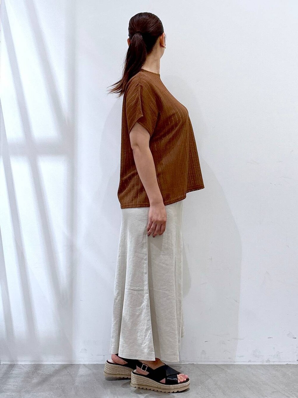 ベージュ系のスカート、ブラック系のハンドバッグ、ブラウン系のTシャツ/カットソーを着用したレディースの夏コーディネートの5枚目の写真