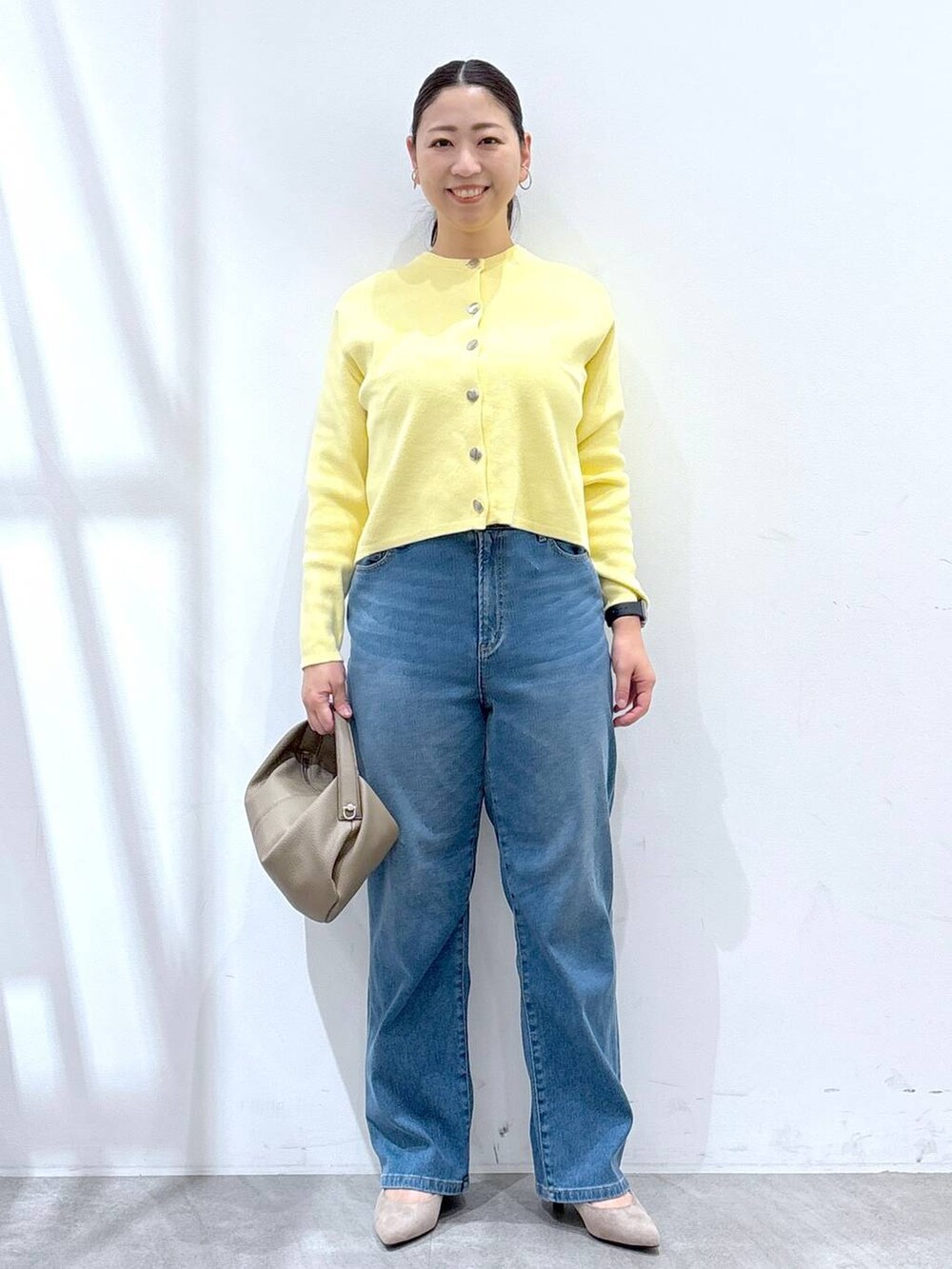 ベージュ系のパンプス、ブルー系のデニムパンツ、イエロー系のカーディガン/ボレロを着用したレディースの冬コーディネートの2枚目の写真