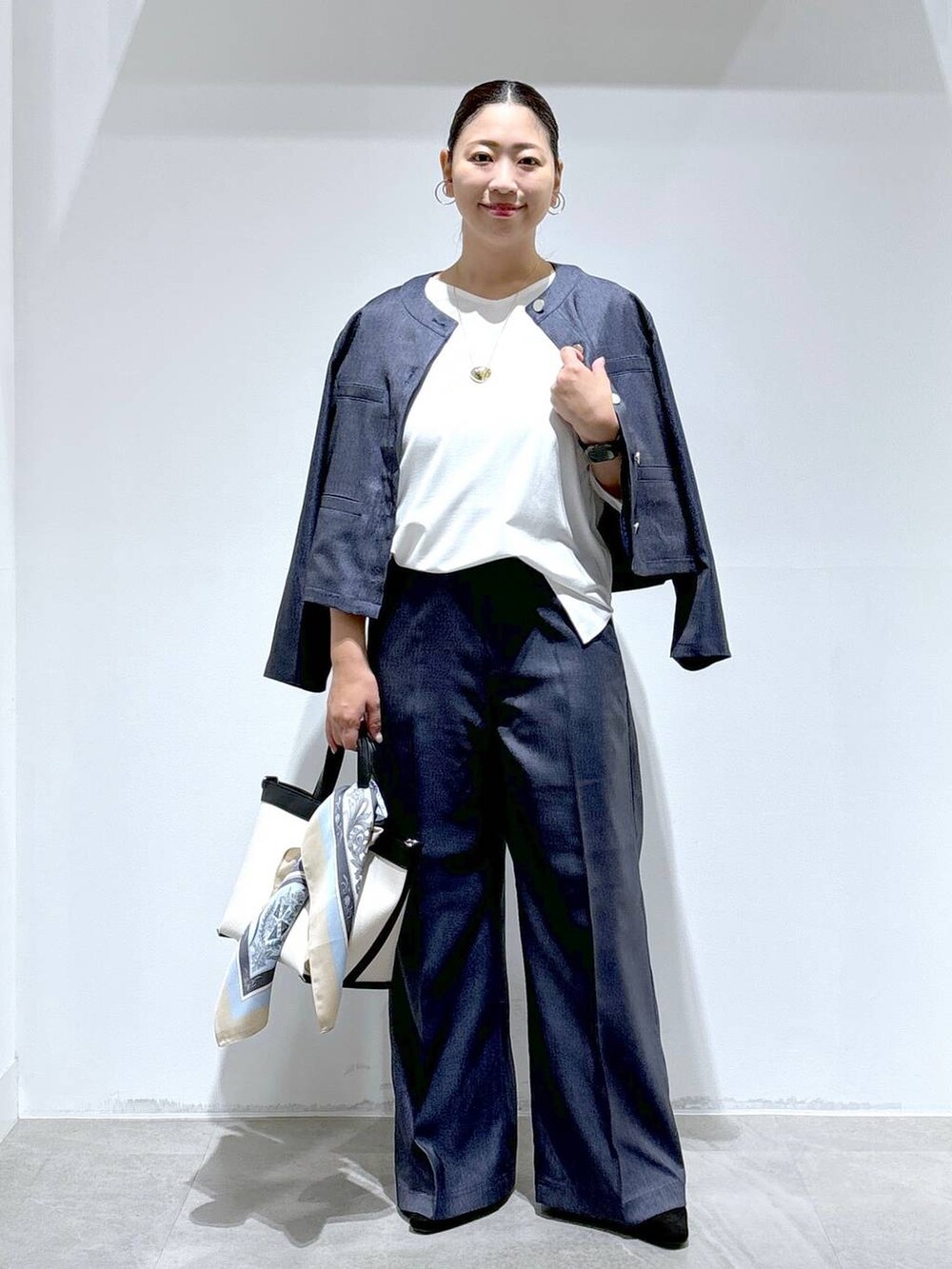 ブラック系のトートバッグ、ブラック系のパンプス、ブルー系のデニムパンツを着用したレディースの秋コーディネートの2枚目の写真