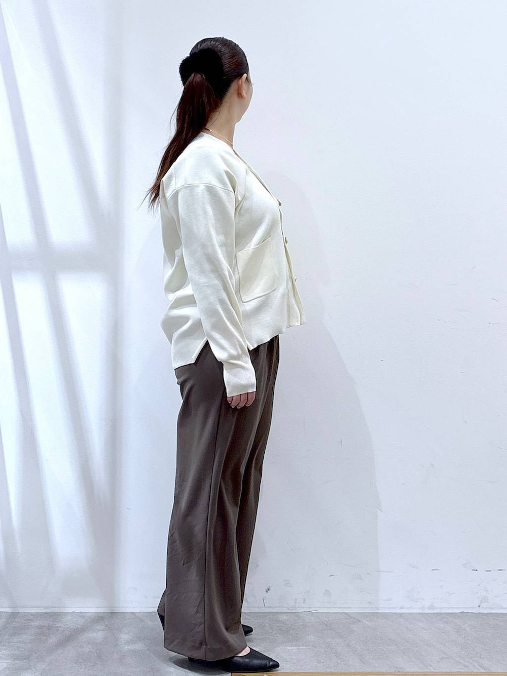 ホワイト系のカーディガン/ボレロ、ブラウン系のその他パンツ、ブラック系のハンドバッグを着用したレディースの冬コーディネートの6枚目の写真