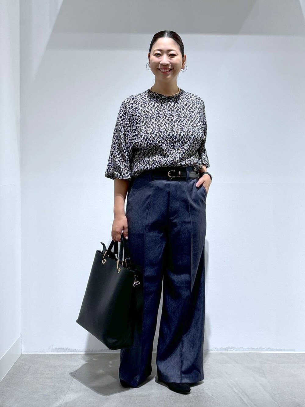 ブラック系のトートバッグ、ブラック系のパンプス、ブルー系のデニムパンツを着用したレディースの秋コーディネートの2枚目の写真