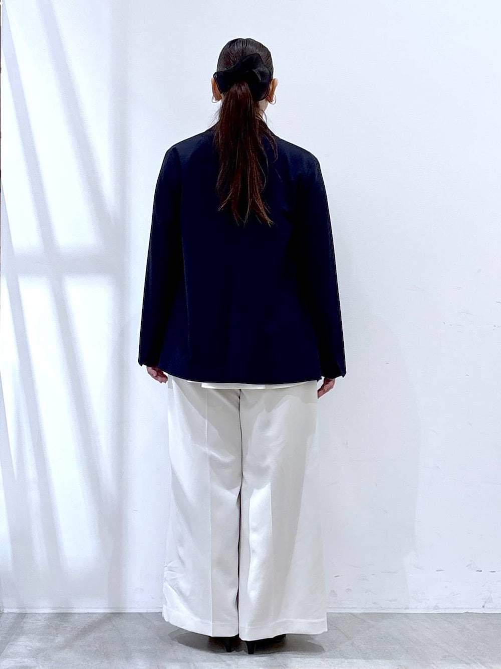 ホワイト系のスラックス、ホワイト系のシャツ/ブラウス、ブラック系のハンドバッグを着用したレディースの冬コーディネートの4枚目の写真