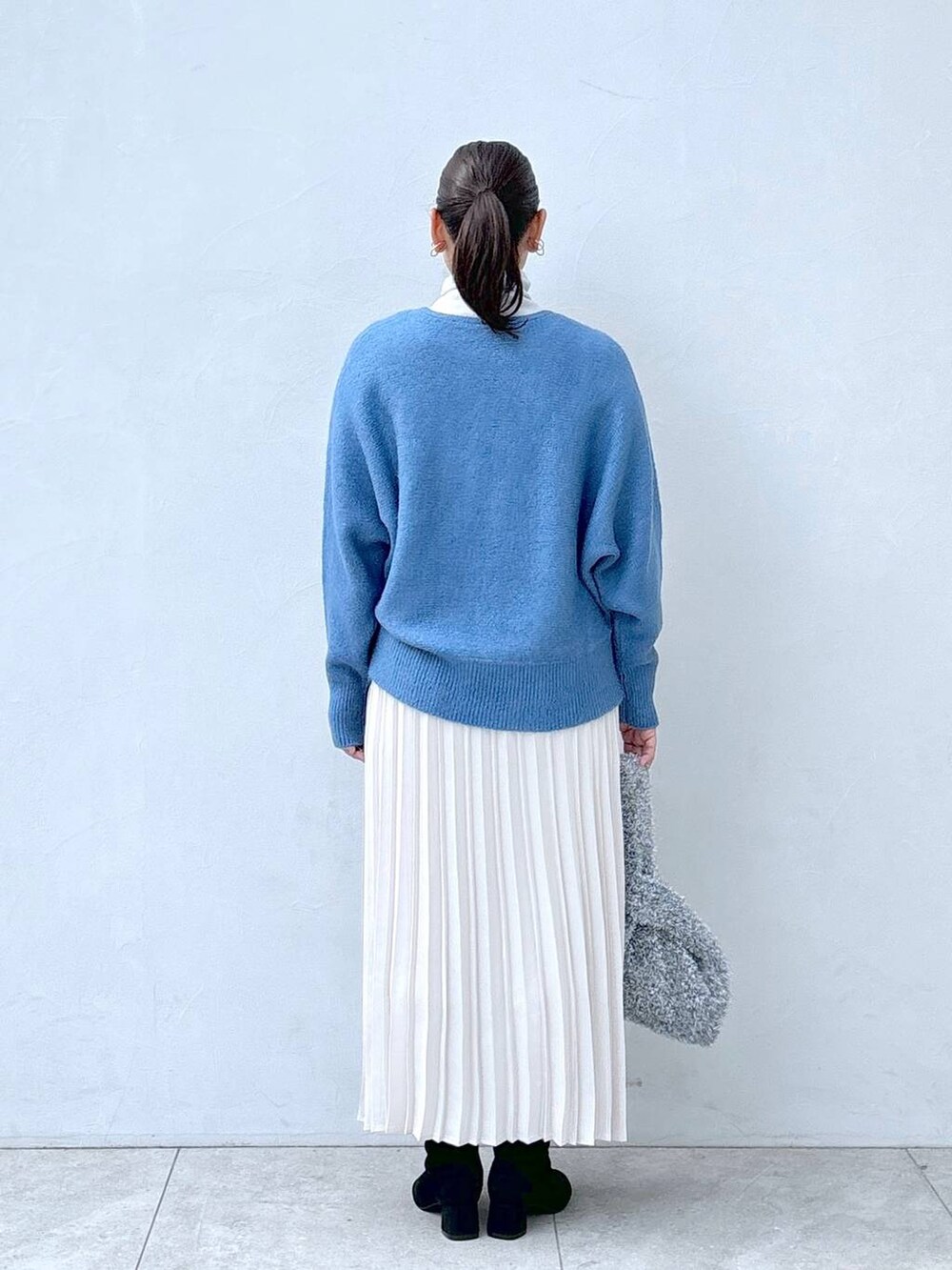 ホワイト系のTシャツ/カットソー、シルバー系のハンドバッグ、グレー系のブーツを着用したレディースの冬コーディネートの4枚目の写真