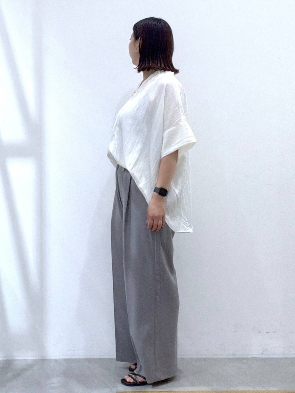 グレー系のその他パンツ、ホワイト系のシャツ/ブラウス、ブラック系のサンダルを着用したレディースの夏コーディネートの3枚目の写真