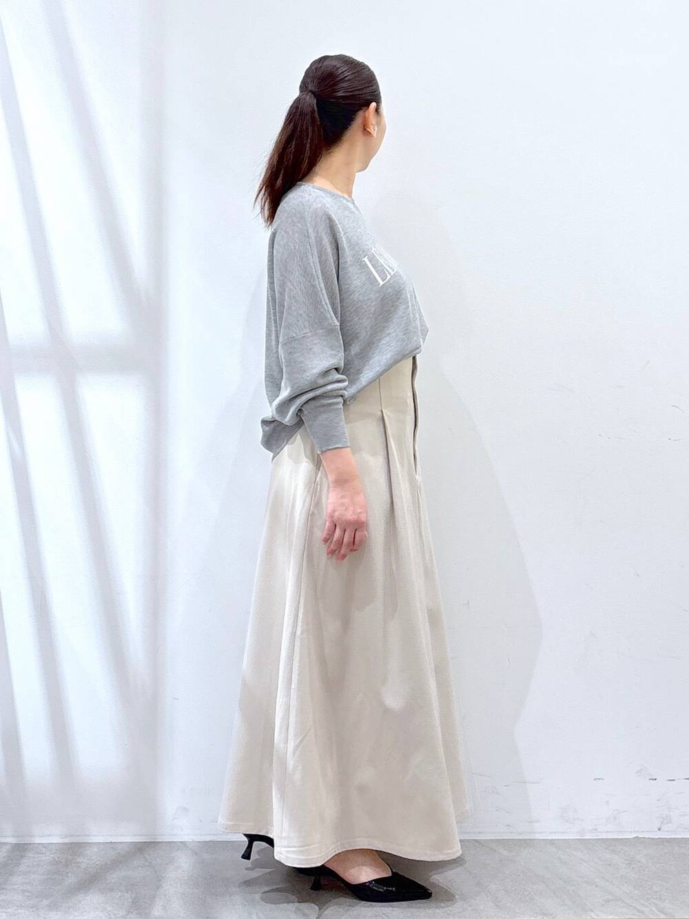 ブラック系のハンドバッグ、グレー系のニット/セーター、ベージュ系のスカートを着用したレディースの春コーディネートの5枚目の写真