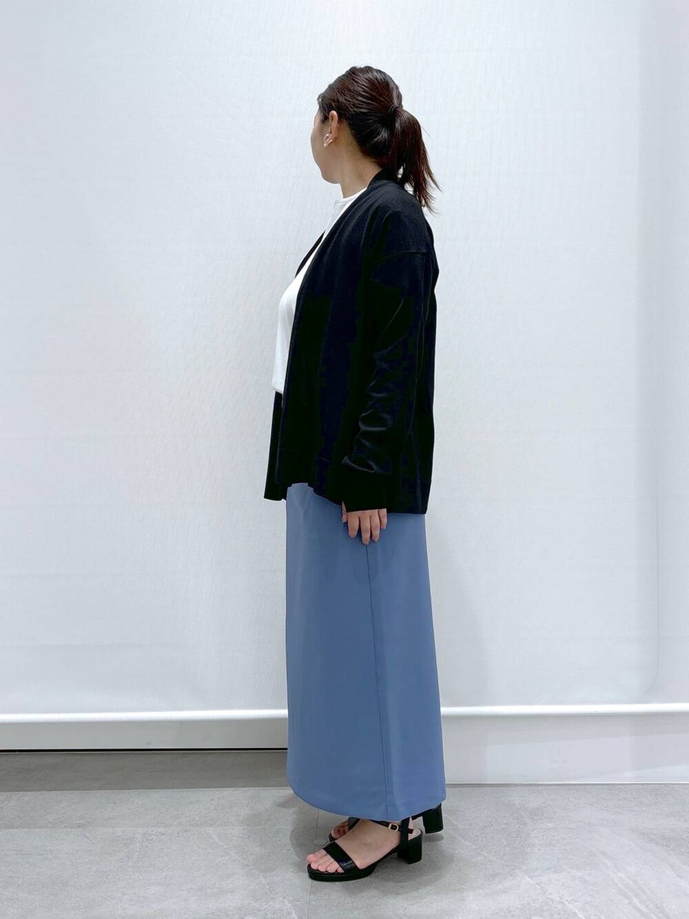 ブラック系のサンダル、ホワイト系のTシャツ/カットソー、ブルー系のスカートを着用したレディースの秋コーディネートの3枚目の写真