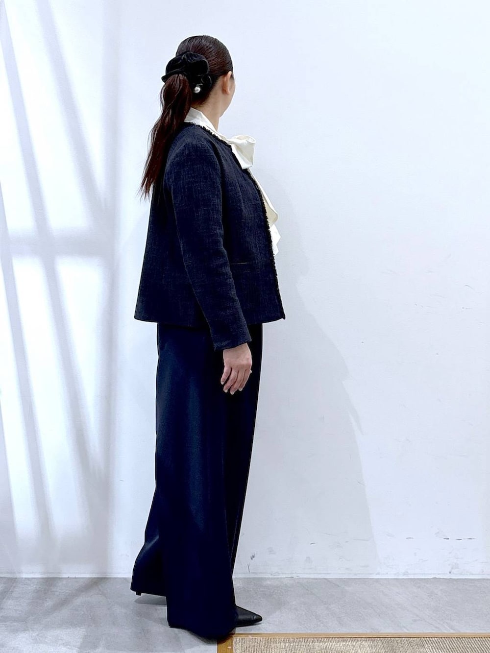 ブラック系のハンドバッグ、ブルー系のノーカラージャケット、ブルー系のスラックスを着用したレディースの冬コーディネートの5枚目の写真