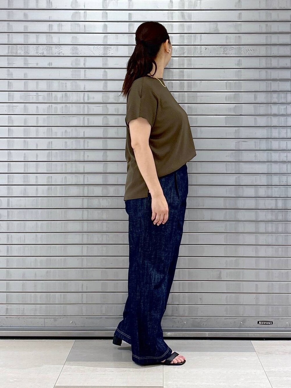 ブルー系のデニムパンツ、ブラック系のハンドバッグ、グリーン系のTシャツ/カットソーを着用したレディースの春コーディネートの5枚目の写真