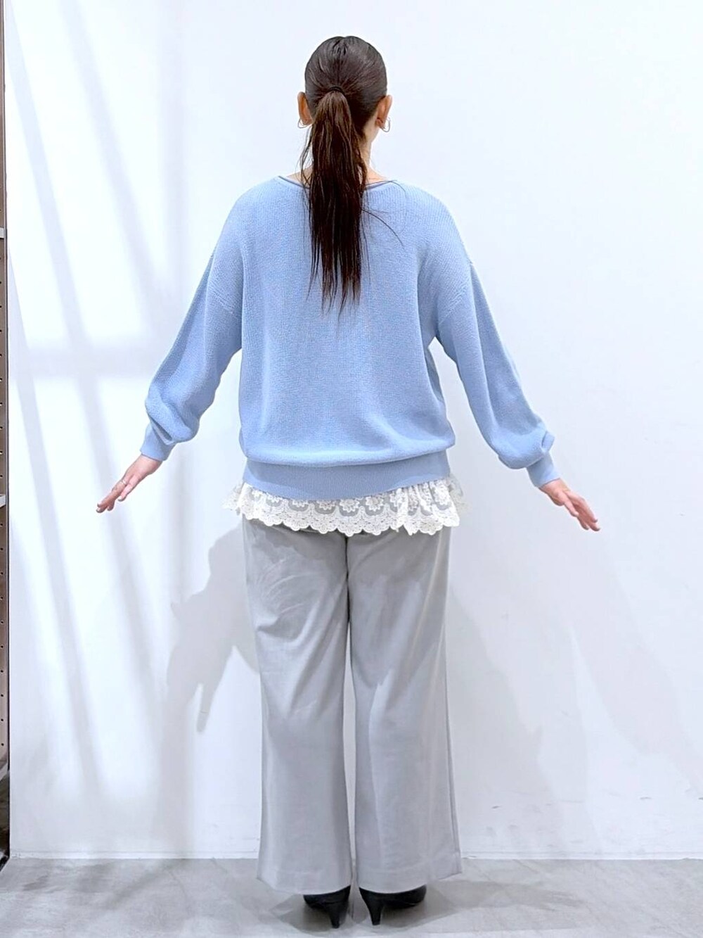 ブルー系のニット/セーター、ホワイト系のタンクトップ、ブラック系のハンドバッグを着用したレディースの春コーディネートの4枚目の写真