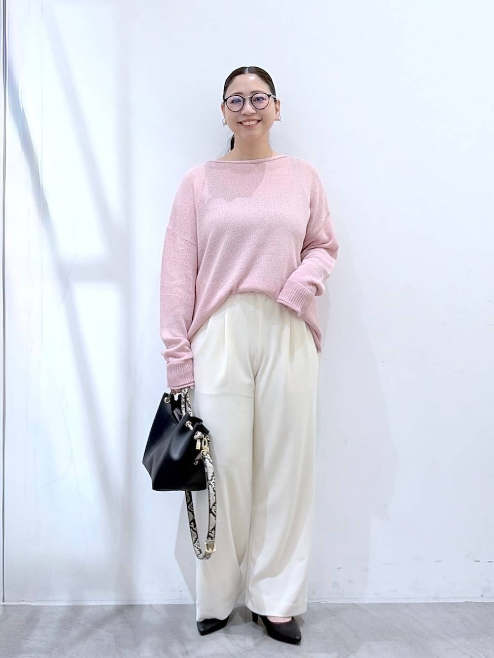 ブラック系のその他パンツ、ピンク系のニット/セーター、ブラック系のハンドバッグを着用したレディースの春コーディネートの2枚目の写真