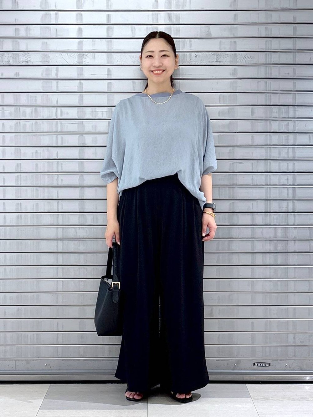ブラック系のハンドバッグ、ブルー系のTシャツ/カットソー、ブラック系のその他パンツを着用したレディースの春コーディネートの2枚目の写真